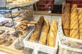 Bakery display case of freshly baked baguettes, croissants and assorted pastries neatly arranged in
