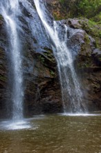 Water from the waterfall running over the rocks inside the rainforest in Minas Gerais, Brazil,