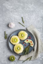 Pieces of baked pork with pineapple, cheese and kiwi on gray background, top view, copy space