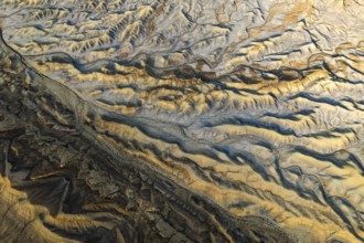Aerial view showcasing the unique textures of a golden sandstone desert in Utah, USA. The sunlight