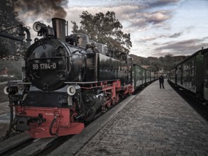 Old, historic steam locomotive in bright colors on tracks at the station in a nostalgic atmosphere,