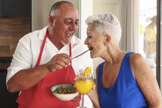 A joyful senior couple engages in a playful and affectionate interaction in a bright kitchen during