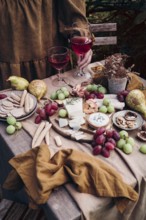 A rustic setup featuring a delicious cheese and fruit platter paired with two glasses of red wine.