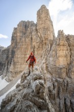 Mountaineer climbs on an exposed rock in the secured Via Ferrata Bocciere Centrale via ferrata,