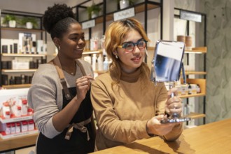 A friendly cosmetics store worker assists a customer trying on products. The customer holds a