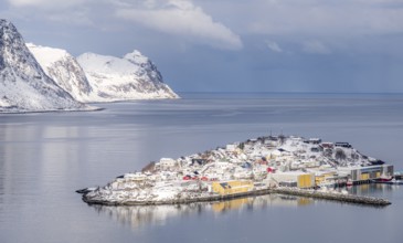 Scenic winter view of Husoy, Norway, with snow-covered houses nestled between serene waters and
