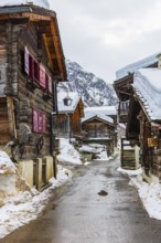 Street with historic old snow-covered wooden houses, mountain village of Zinal, Val d'Anniviers,