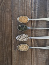 Various healthy seeds filling spoons on a rustic wooden background