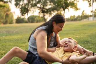 A mother lovingly embraces her son with cerebral palsy as they enjoy a sunny day in the park. They