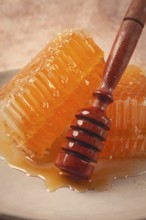 Honeycomb, with a wooden spoon-spindle, on a plate, no people
