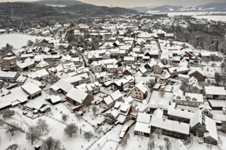 Village in winter with snow-covered half-timbered houses and trees under grey skies, Herleshausen