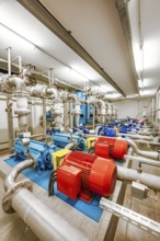 Machines with metal pipes and illuminated pumps in a technical room, ENCW Netze Calw waterworks,