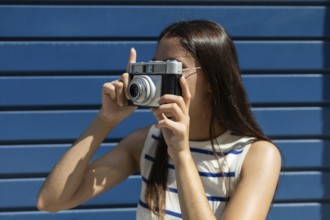 A young woman joyfully explores city life through the lens of a vintage camera, embodying the