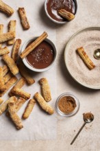 Top view of homemade churros generously dusted with sugar and cinnamon, accompanied by a rich