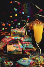 Colourful pieces of cake with sparkling wine and flying chocolate drops in a lively party
