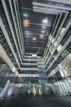 Modern building complex with illuminated inner courtyard and glass structure, Stuttgart, Germany