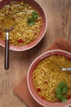 Enjoy a hearty grain soup featuring a vibrant mix of ingredients served in two rustic bowls,