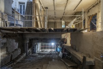 A construction site inside a partially renovated building features an exposed concrete structure,