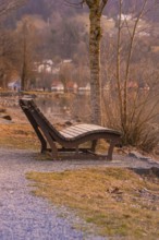 Wooden chair on the lakeside in autumnal weather, quiet atmosphere with warm light, Großer Alpsee,