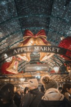 Visitors to Apple Market surrounded by Christmas bells and a sign with handmade art & design,