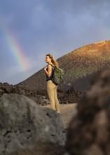 A woman with a backpack explores the volcanic landscape of Timanfaya National Park in Lanzarote. A