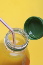 Orange juice in plastic bottle with cap and straw