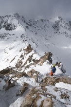 Mountaineer descending the narrow ridge of Piz Laviner, view of mountain panorama in wintry