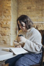 A young woman sits in a charming bookstore, engrossed in a book, while enjoying a hot coffee The