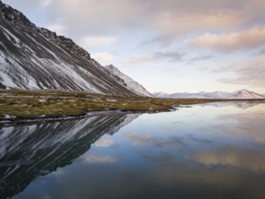 Breathtaking winter landscape of Iceland featuring snow-capped mountains and their reflection in