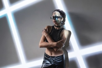 A woman embodies a cyberpunk aesthetic, wearing reflective sunglasses and a studded outfit. The