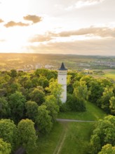 A tower embedded in blossoming trees, flooded with sunset light, Engelberg Tower, Leonberg, Germany