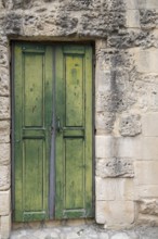 Old green wooden door in a weathered stone wall. Rustic and historic appearance, Matera historic