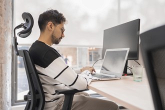 A professional concentrates on his laptop in a modern office environment Natural light illuminates