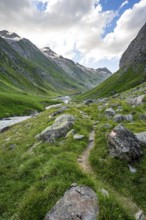 Hiking trail in the Umbaltal valley with Isel mountain stream, glaciated mountain peaks behind,