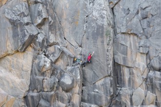 Climbers scale a rugged cliff using traditional techniques, highlighting skill, adventure, and a