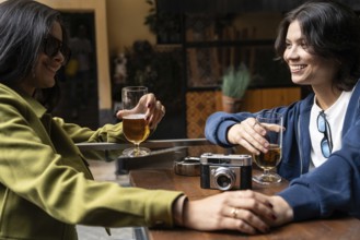 A couple enjoys each other's company over drinks at an outdoor cafe. They are relaxed and smiling,