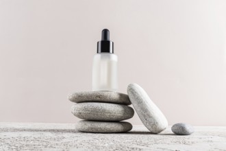 A minimalist skincare concept with a frosted glass dropper bottle placed elegantly on a stack of