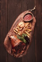 Pork knuckle, in soy-honey sauce, with fried potatoes, on a wooden chopping board, homemade, no