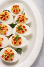 Stuffed eggs, with red caviar, micro greenery, Snack, on a white plate, top view, close-up, no