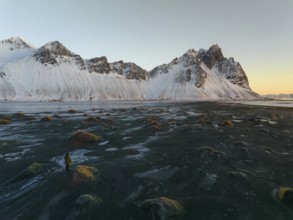 A stunning winter view of Stokksnes Beach in Iceland, featuring rugged snow-capped peaks against a