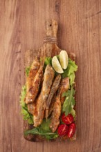 Fried crispy red mullet fish, on a wooden chopping board, with lime, no people