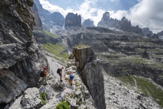 Three mountaineers in front of picturesque mountain landscape with rocky peaks, Via Ferrata SOSAT