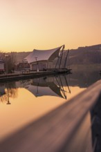 Large tent next to a pier by the lake, quiet atmosphere at dusk and reflection in the water, Großer