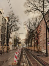A street with construction site of tram tracks and rainbows populated by bare trees, Pankow, Berlin