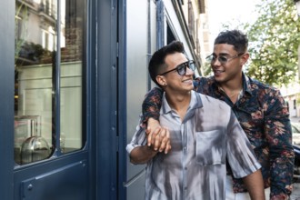 A cheerful latin gay couple walks hand in hand on a sunny day in Madrid. They share smiles and