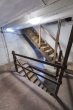 Interior view with wooden staircase and stony floor in a historic building, Prison Museum, Der