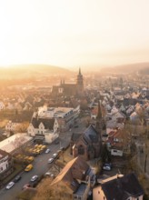 A church and a village in the evening light with a view of hills and trees, Weil der Stadt,