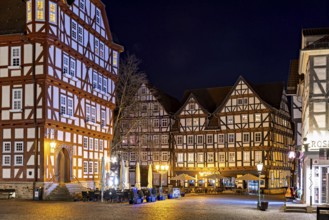 Night scene with illuminated half-timbered houses and a café in a rustic setting, The old town