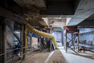 A construction site undergoing structural reinforcement features steel supports, exposed concrete