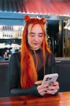 A young woman with vibrant red hair checks her phone in a lively market ambiance, blending modern